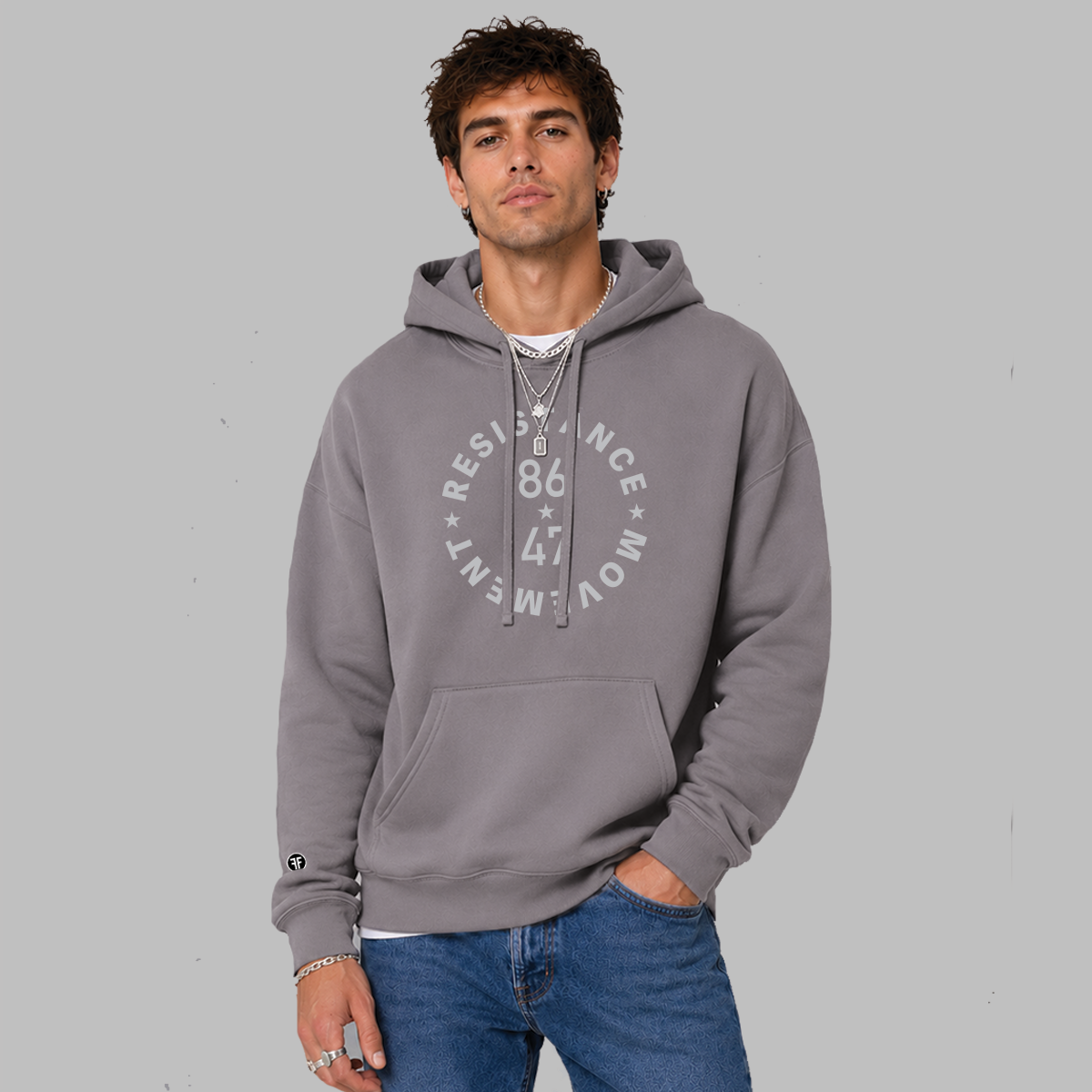 A man wearing a slate purple colored, unisex political hoodie. The grey text says "86 47"in the middle with"Resistance Movement" around it.