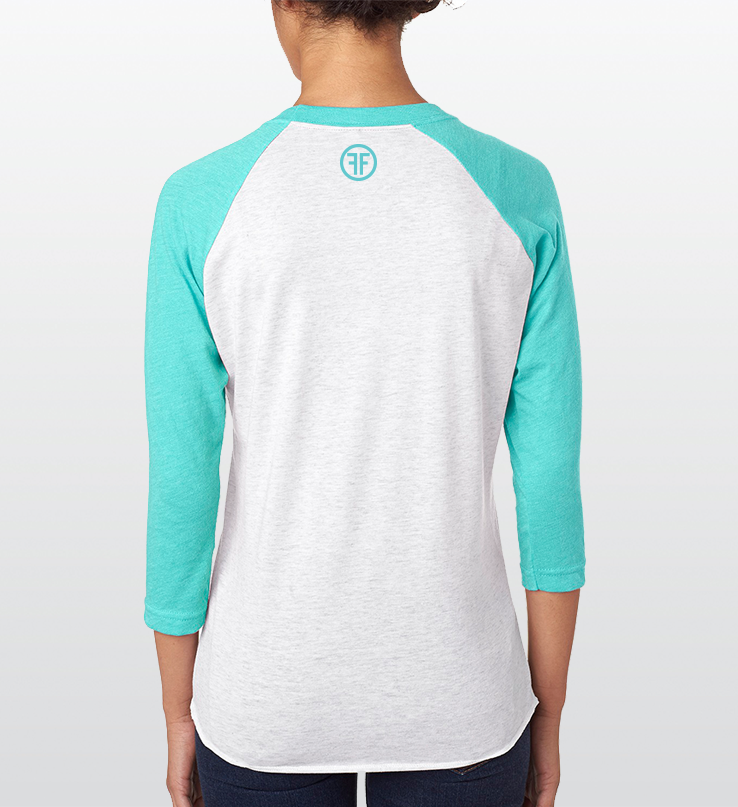 The back of a lady wearing a light grey baseball Pride t-shirt that has aqua arms and collar. An aqua logo is below the collar, with two Fs back to back in an aqua circle.