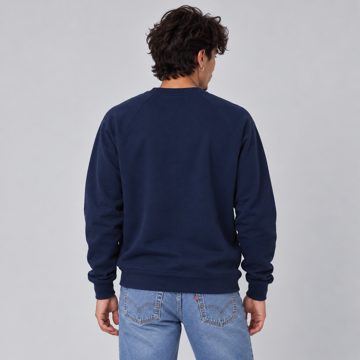 A man viewed from behind wearing a navy blue crewneck sweatshirt showing a standard unisex fit and no graphics or logos.