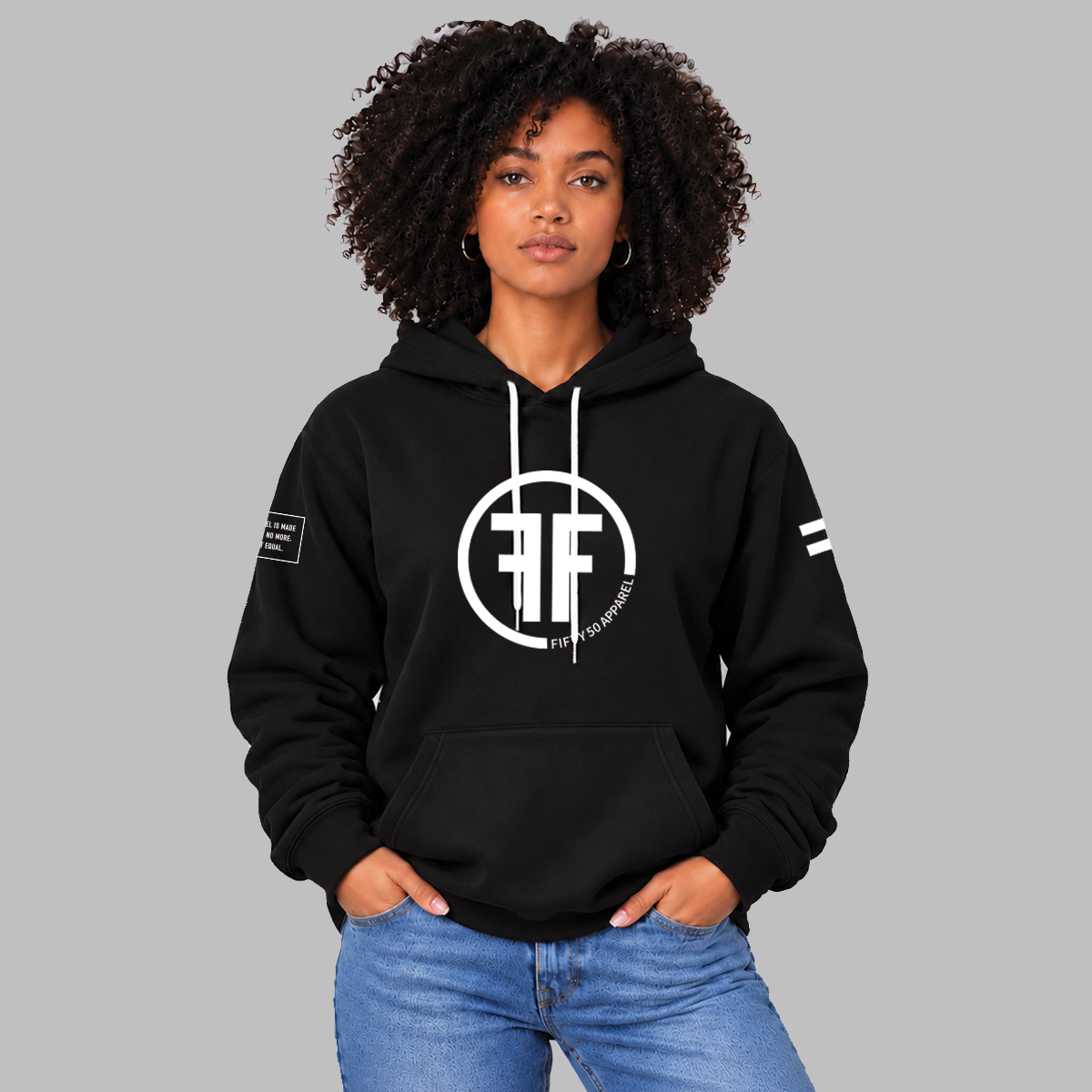 A lady wearing a unisex hoodie with a white equal sign on left arm, and the text, 'Fifty 50 Apparel is made for equality, no more, no less, just equal', on the right arm.  Center chest logo has two Fs, back to back with a circle symbolizing balance and equality.