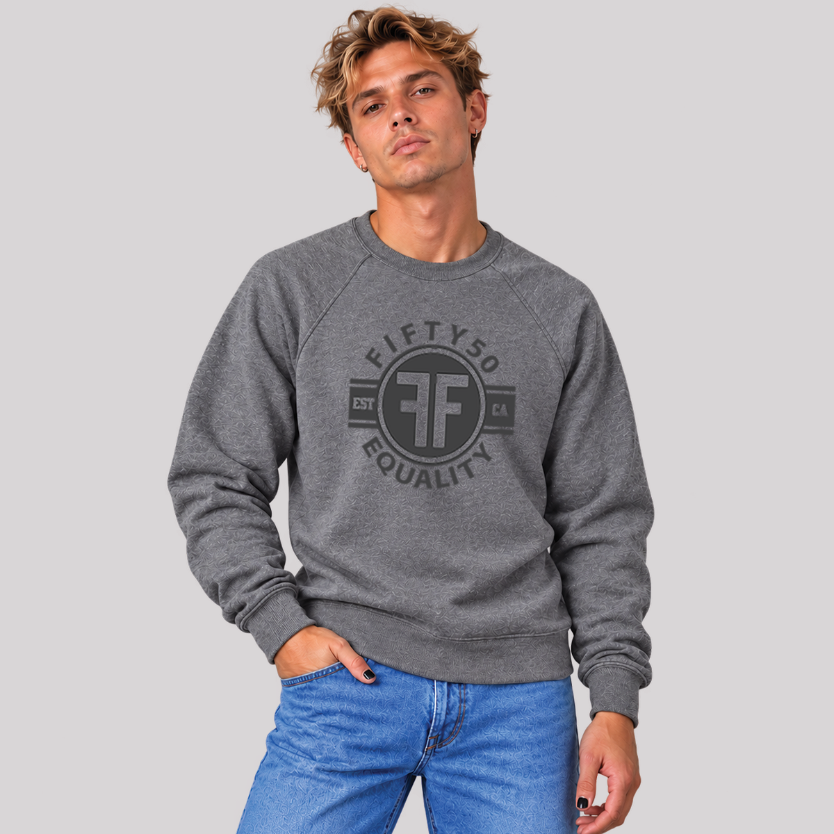 A man wearing a heather grey equality crew sweatshirt. The black graphic says 'Fifty50, Equality'  and has two Fs, back to back in a circle.
