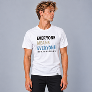 A man wearing a white graphic t-shirt with the text 'EVERYONE MEANS EVERYONE NO EXCEPTIONS' in black, tan, and slate blue printed on the front, paired with black pants, set against a solid gray studio background.