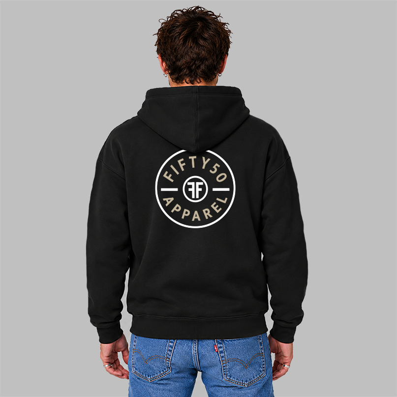 A man viewed from behind wearing a black pullover hoodie with a circular  large center back graphic that reads 'FIFTY50 APPAREL' in tan, with a white circle around it. The middle of the graphic has two white Fs back to back.