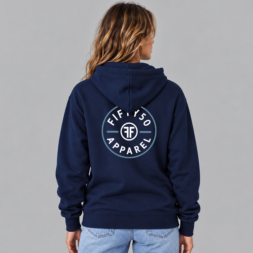 A woman viewed from behind wearing a navy blue pullover hoodie with a circular  large center back graphic that reads 'FIFTY50 APPAREL' in white, with a Slate Blue circle around it. The middle of the graphic has two white Fs back to back.