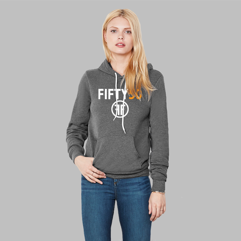 A lady wearing a heather grey hoodie with a logo. The text Fifty is in white bold font and the number fifty is in orange bold font. Under the text are two white Fs, back to back, surrounded by a circle. 