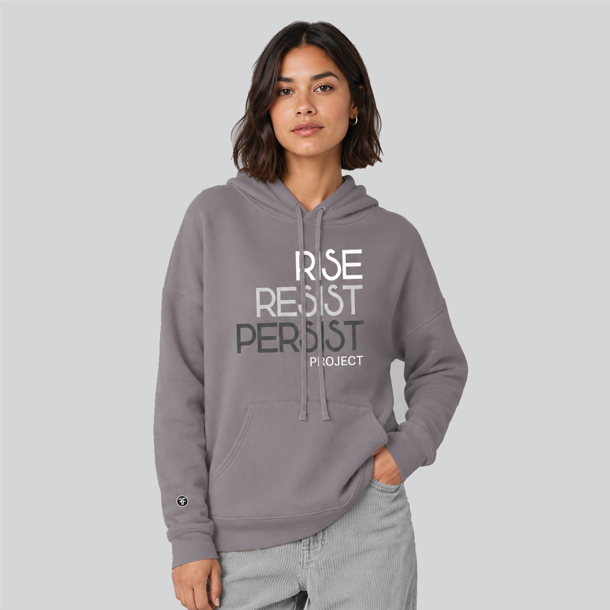 A woman wearing a gray pullover hoodie with the text 'RISE RESIST PERSIST' and 'PROJECT' printed on the front, paired with light gray jeans, against a solid gray background.