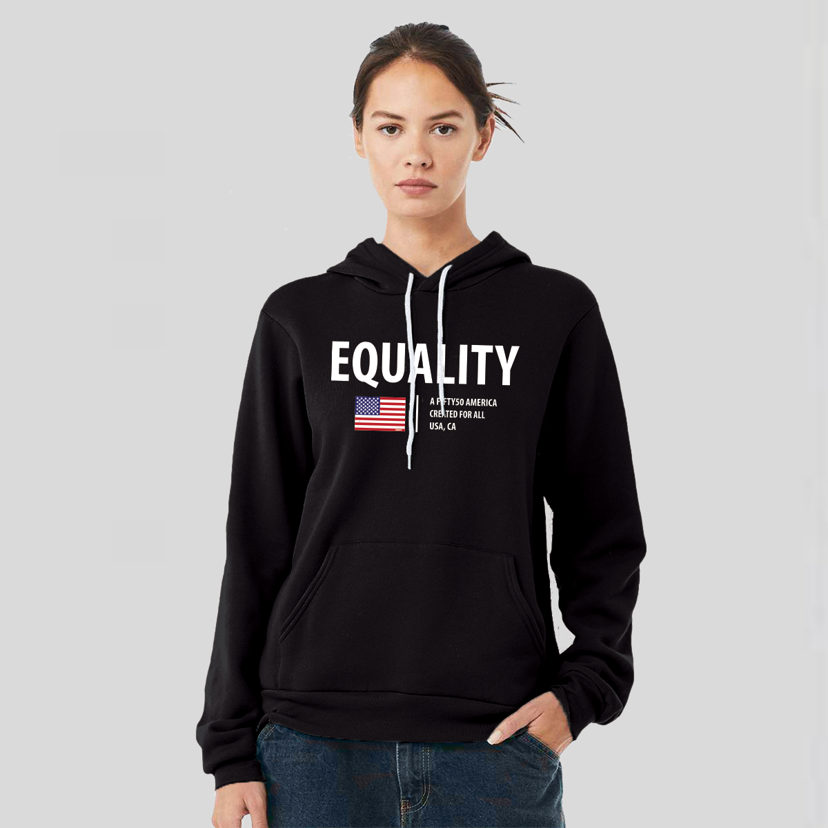 A lady wearing a black hoodie. The logo has the text, Equality, written in white bold font, and an American flag and the text, A fifty 50 America created for all.
