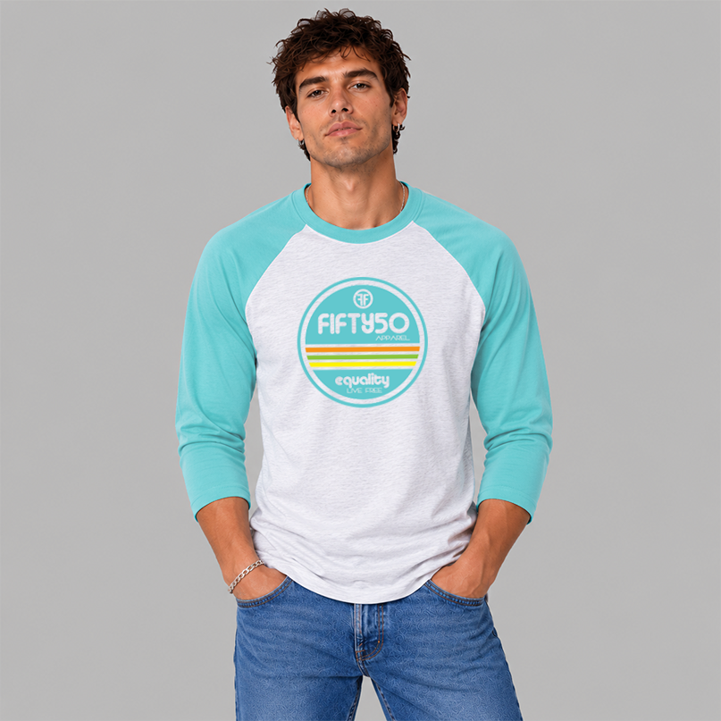 A man wearing a light grey baseball Pride t-shirt, standing for equality, that has aqua arms and collar. The graphic is round in aqua, orange, green, and yellow, and the text says 'Fifty 50 Equality, Live Free.'