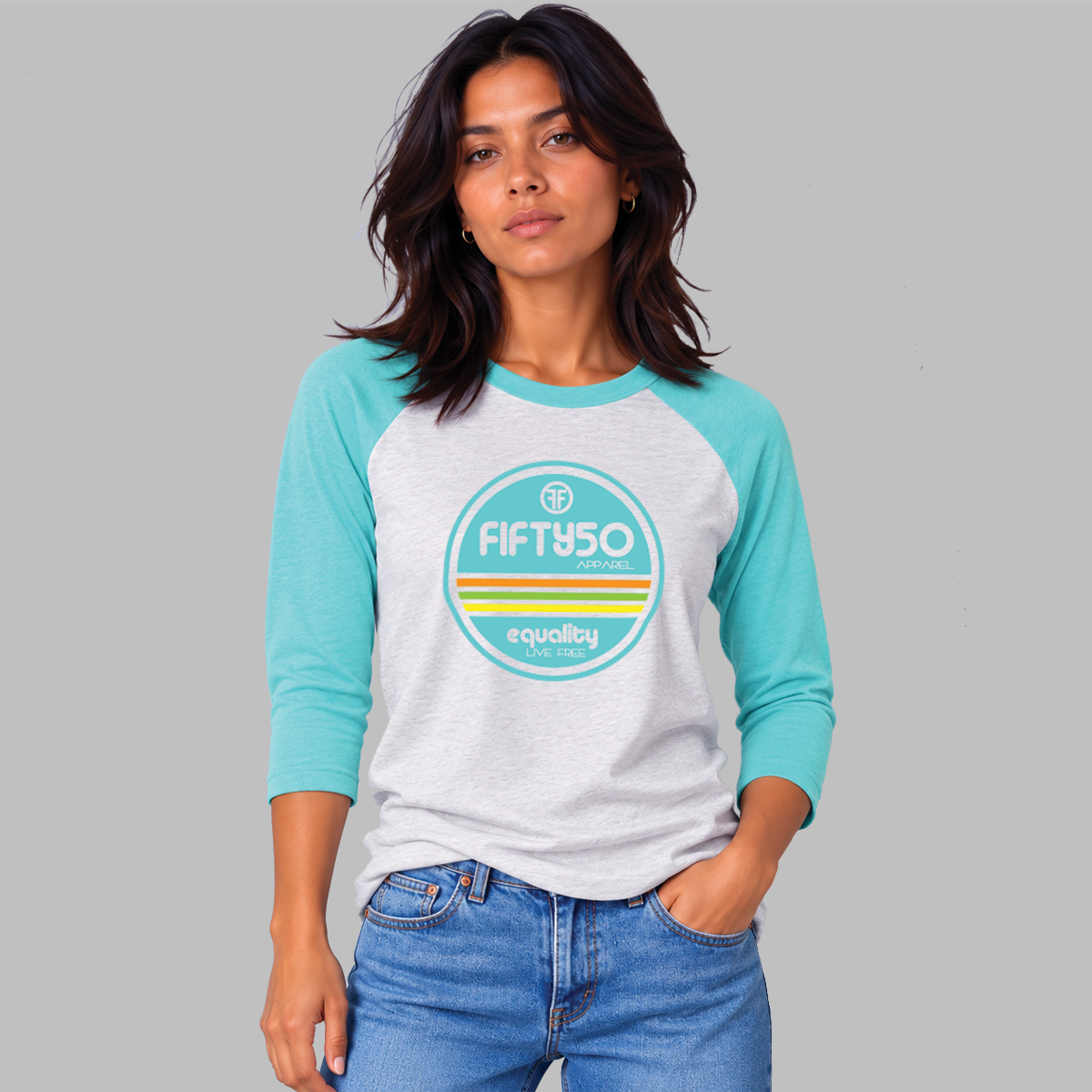 A lady wearing a light grey baseball Pride t-shirt, standing for equality, that has aqua arms and collar. The graphic is round in aqua, orange, green, and yellow, and the text says 'Fifty 50 Equality, Live Free.'