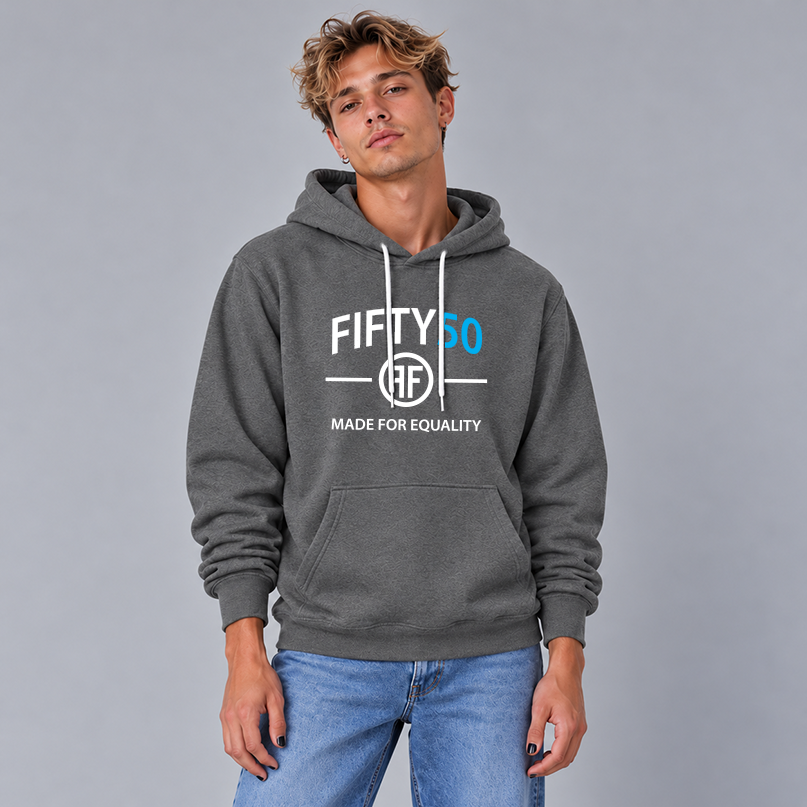 A man wearing a dark gray pullover hoodie with a white and turquoise graphic print that reads 'FIFTY50 MADE FOR EQUALITY' and two Fs back to back in the middle, paired with blue jeans, against a solid gray studio background.
