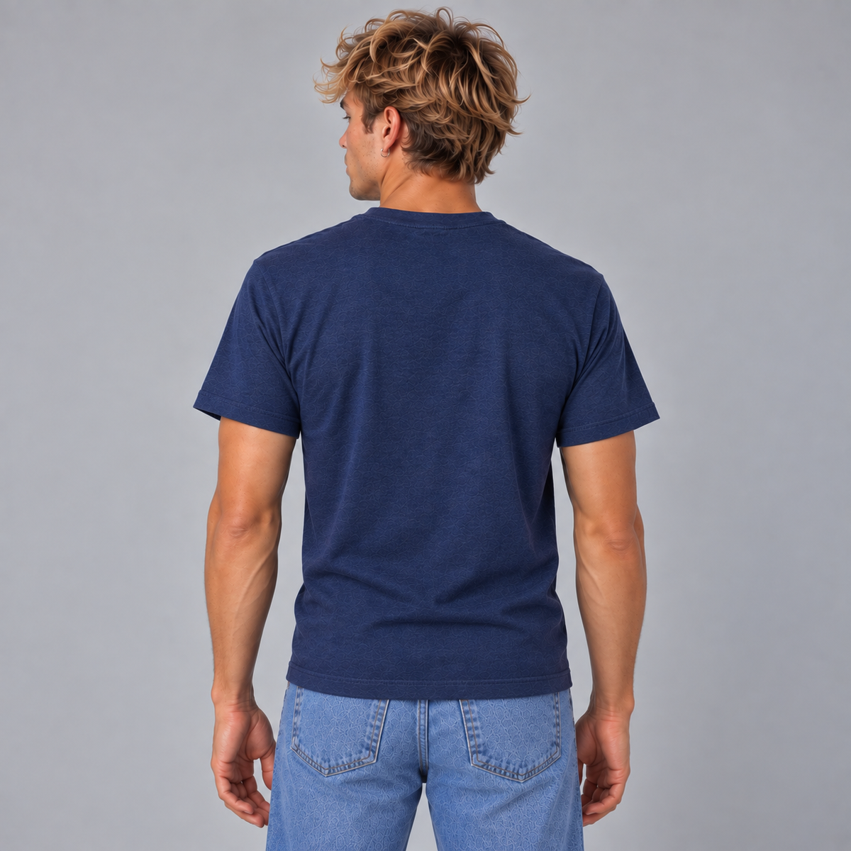 A man viewed from behind wearing a navy blue short-sleeve crewneck t-shirt showing a unisex fit and that there are graphics or design on the back of the shirt.