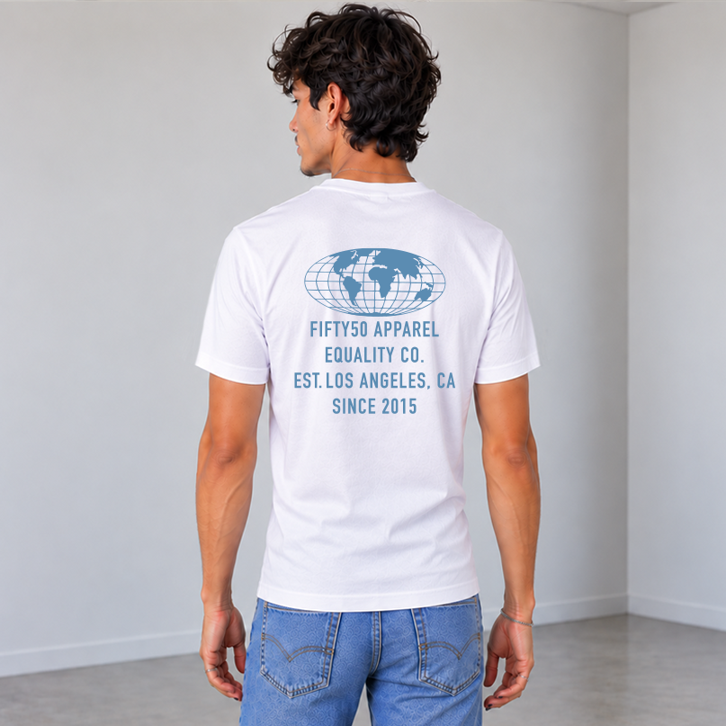 A man viewed from behind wearing a white t-shirt with a Slate Blue graphic print on the back of a globe and the text 'FIFTY50 APPAREL EQUALITY CO, LOS ANGELES, CA, SINCE 2015, paired with blue jeans, against a solid gray studio background.
