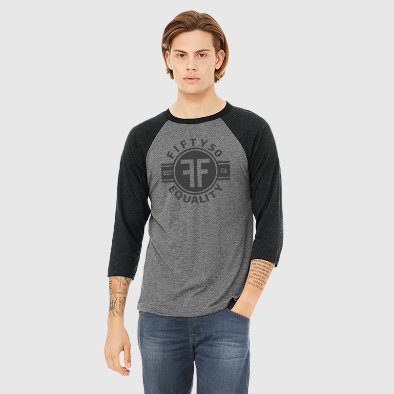 Man wearing a heather grey equality baseball tshirt with heather black arms and collar. The text of the black graphic says Fifty50, Equality, and has two Fs, back to back in a circle.