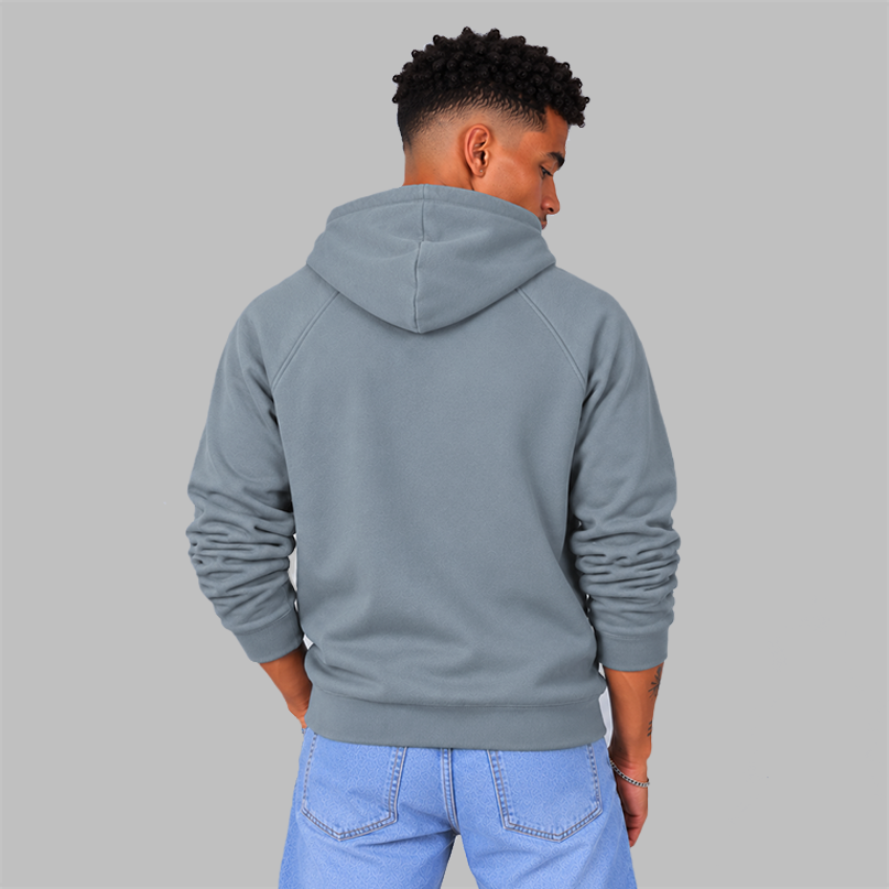 The back of a man wearing a slate light blue pullover hoodie, showing the unisex fit and there are no graphics,  paired with light blue jeans against a solid gray studio background.