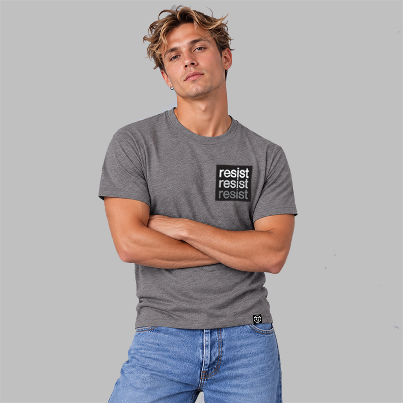 A man wearing a heather slate purple crewneck t-shirt with a black square chest graphic that reads 'resist resist resist' in white, light grey and grey text, paired with blue jeans, against a solid gray background.
