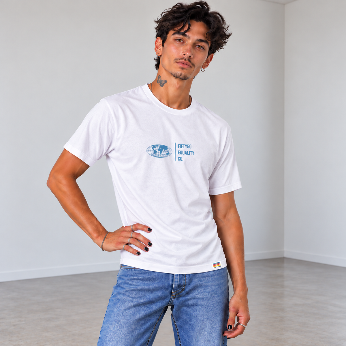 A man wearing a white short-sleeve t-shirt with a Slate Blue graphic center chest featuring a globe and the text 'FIFTY50 EQUALITY CO. Paired with jeans, set against a solid gray background.