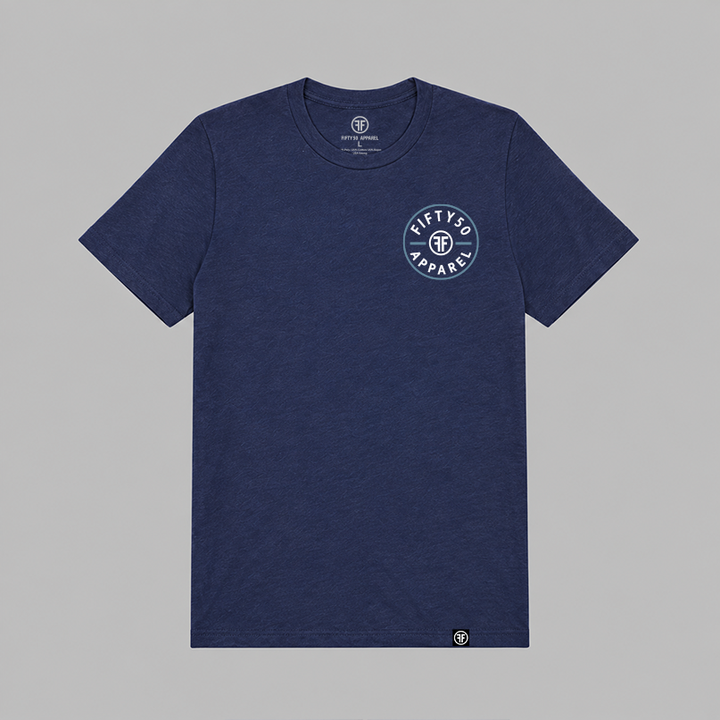 A navy blue heather crewneck t-shirt with a circular white and light blue graphic on the left chest reading 'FIFTY50 APPAREL'. The shirt is displayed flat against a solid gray background.