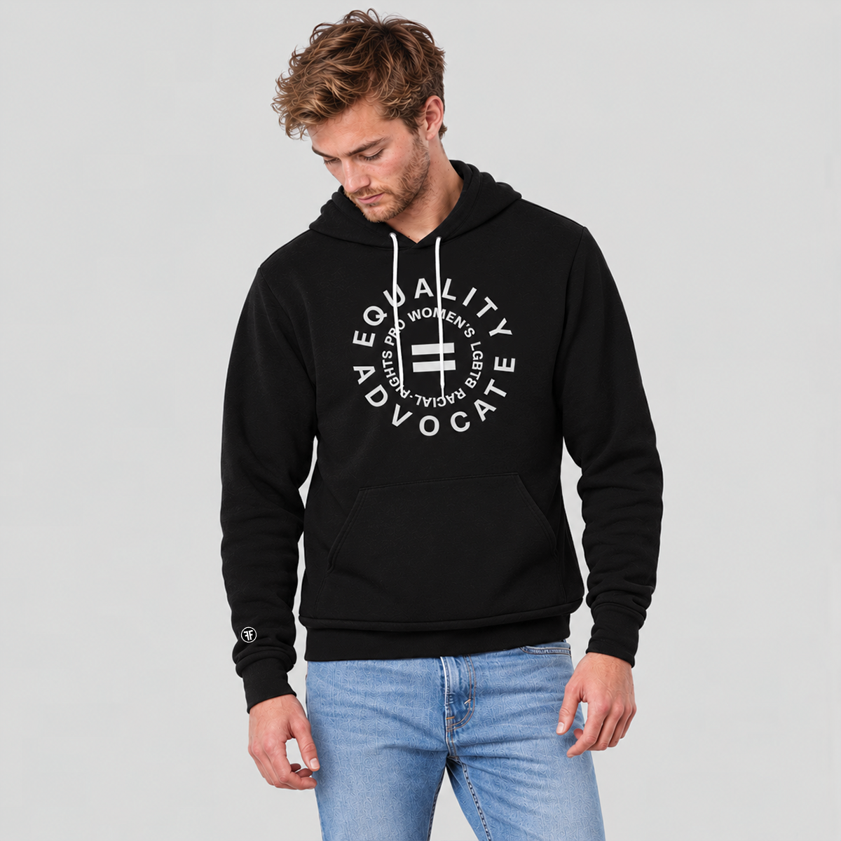 A man wearing a black pullover hoodie with a light grey circular graphic on the chest that reads 'EQUALITY ADVOCATE' and 'PRO WOMEN'S, LGBT, RACIAL RIGHTS, paired with light blue jeans, against a solid light gray background.