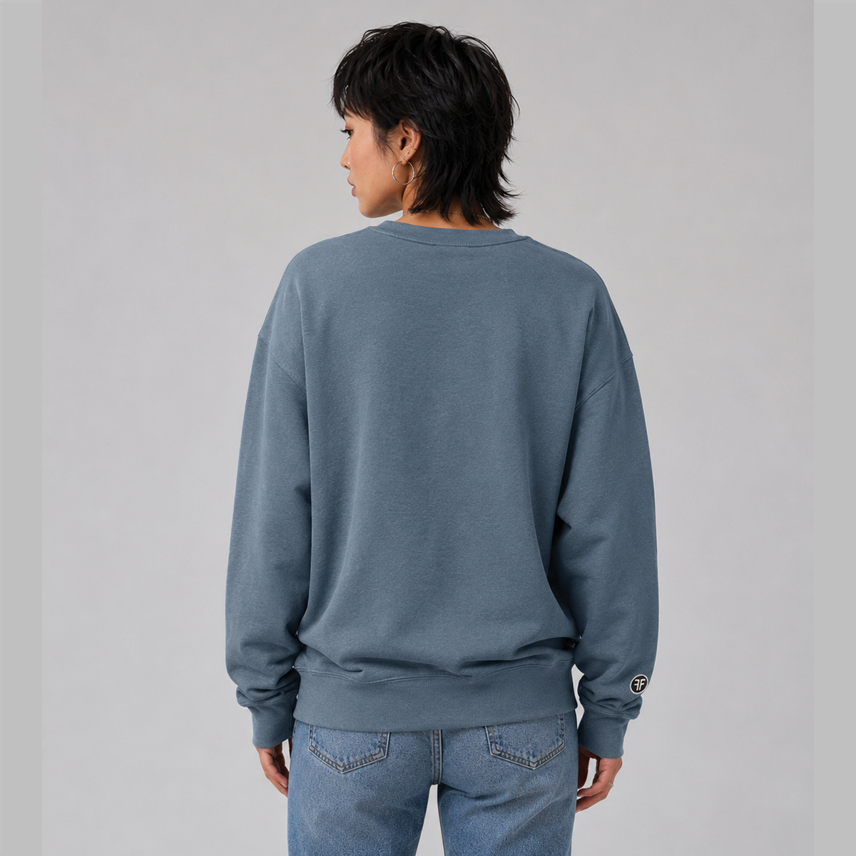 The back of a lady wearing a political hoodie that is Slate Blue. It shows a loose fit and that there are no graphics.