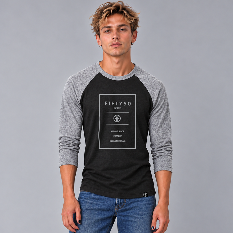 A man wearing a 3/4 sleeve heather black baseball t-shirt with heather grey arms and collar. The logo is a grey rectangle with the grey text Fifty 50, and Apparel Made For True Equality for All inside of it.