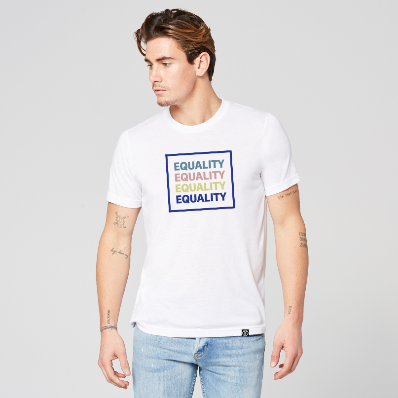 A man wearing a white equality tshirt with the text Equality, stacked four times in a row, in navy blue, Slate Blue, Dusty Rose, and Bisque Gold. The text is in bold font and is outlined by a navy blue square.  