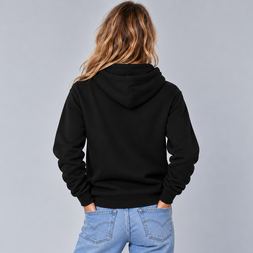 A woman shown from the back wearing a plain black pullover hoodie to show the unisex fit and that there are no graphics on the back. She is wearing light blue jeans against a light gray studio background.