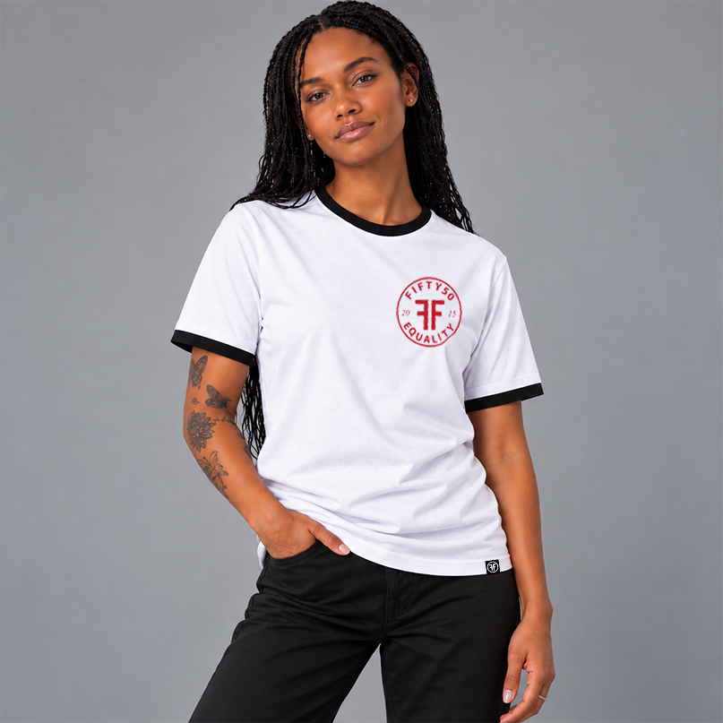 A woman wearing a white ringer t-shirt with black trim on the collar and cuffs, featuring a red circular chest graphic that reads 'FIFTY50 EQUALITY 2015'.