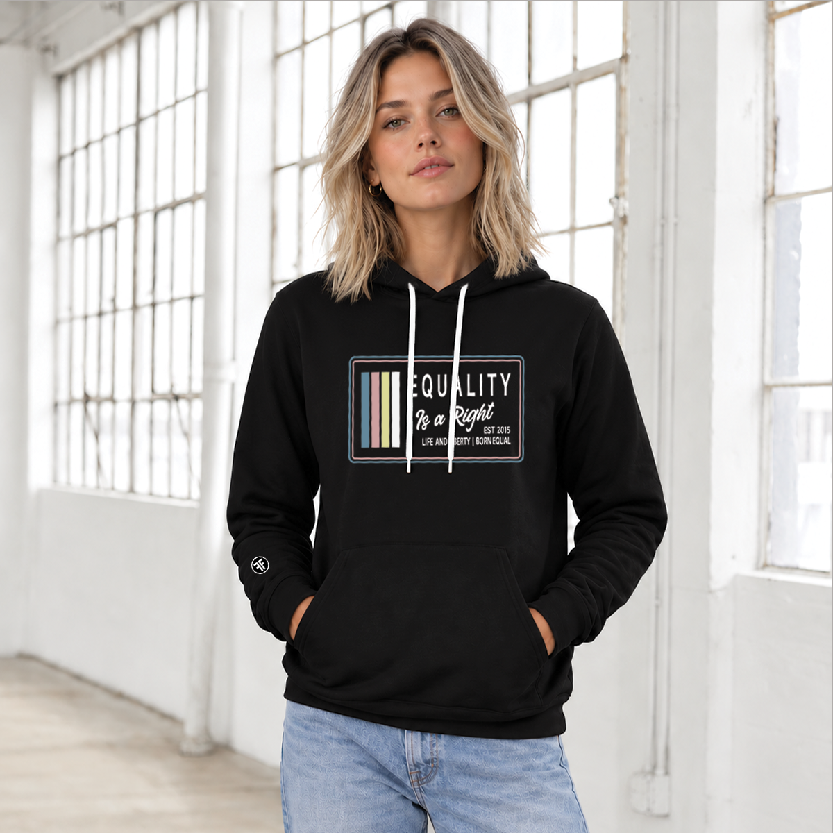A woman wearing a black pullover hoodie with a graphic print on the front, that says 'EQUALITY IS A RIGHT LIFE AND LIBERTY BORN EQUAL'