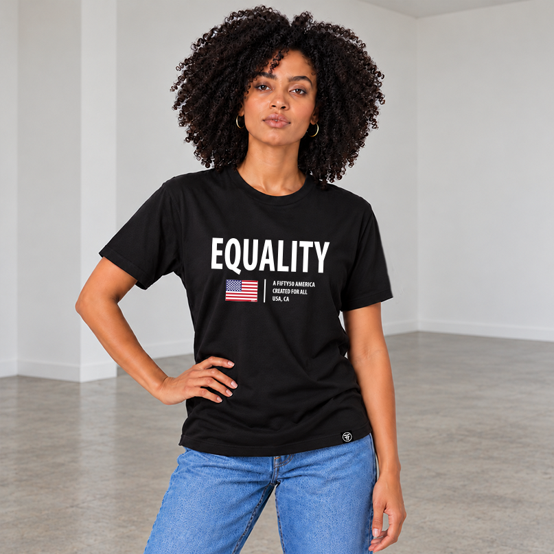 A woman with curly dark hair stands in a minimalist white room wearing a black graphic T-shirt with the word 'EQUALITY' in white, a small American flag graphic, and text reading 'A FIFTY50 AMERICA CREATED FOR ALL, USA CA.' 
