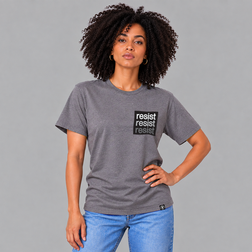 A woman wearing a heather slate purple crewneck t-shirt with a black square chest graphic that reads 'resist resist resist' in white, light grey and grey text, paired with blue jeans, against a solid gray background.
