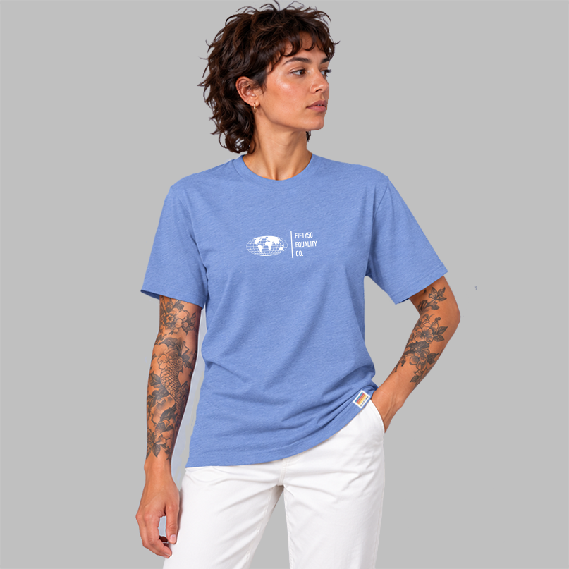 A man wearing a  blue short-sleeve t-shirt with a white graphic center chest featuring a globe and the text 'FIFTYT50 EQUALITY CO. Paired with white pants, set against a solid gray background.