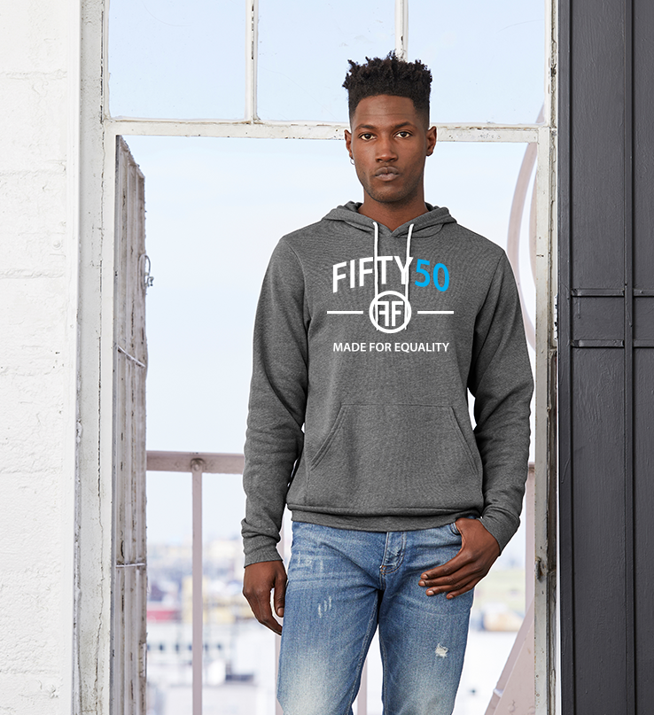 A  man wearing a charcoal grey hoodie with a logo. The text on the tee is in white and turquoise and reads Fifty50 and Made for Equality.